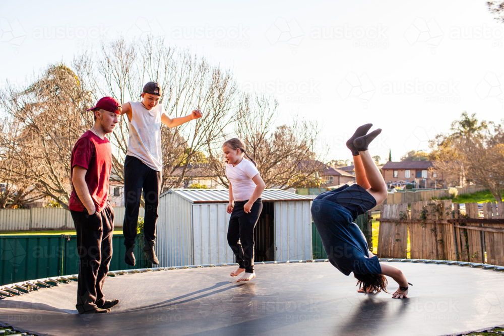 Australian kids doing backflips on a trampoline without an enclosure in backyard - Australian Stock Image