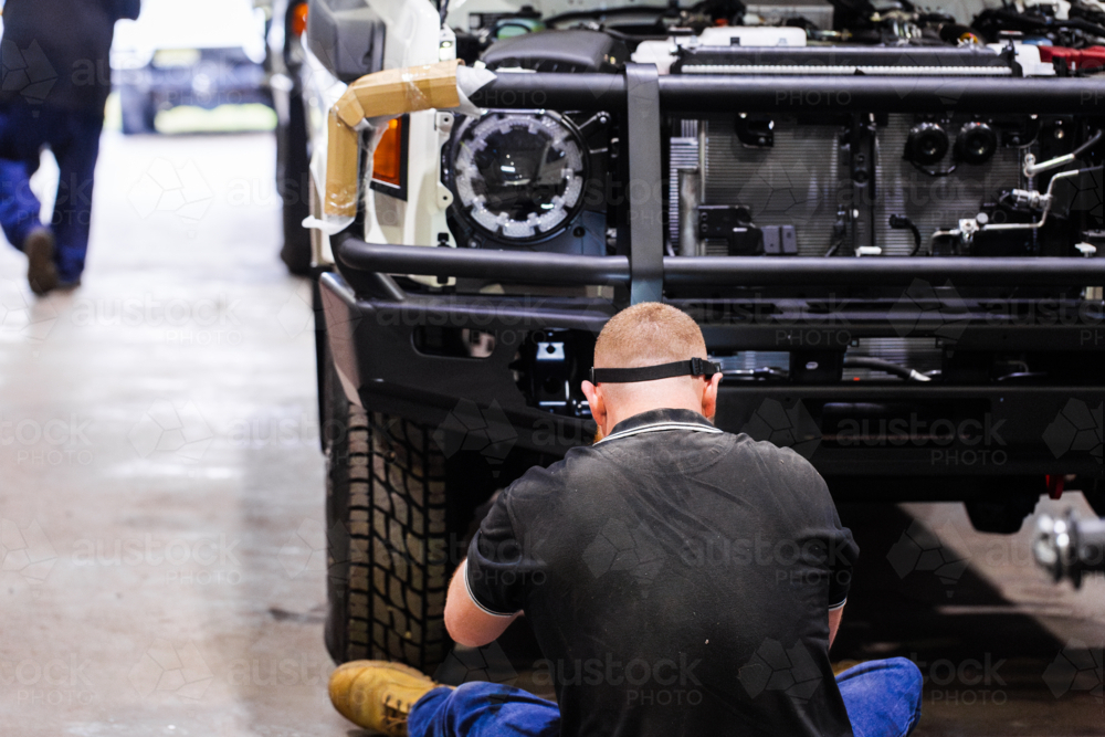 Image of Australian man installing bull bar onto vehicle in mechanic ...