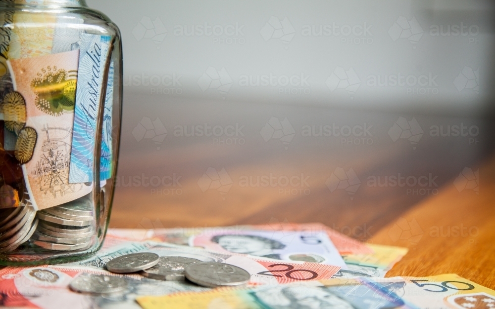 Australian money in notes and coins on wooden background with jar - Australian Stock Image