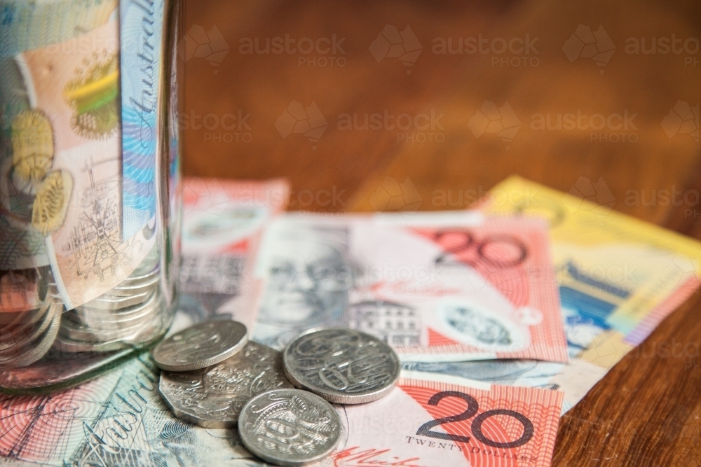 Australian money in notes and coins on wooden background with jar - Australian Stock Image