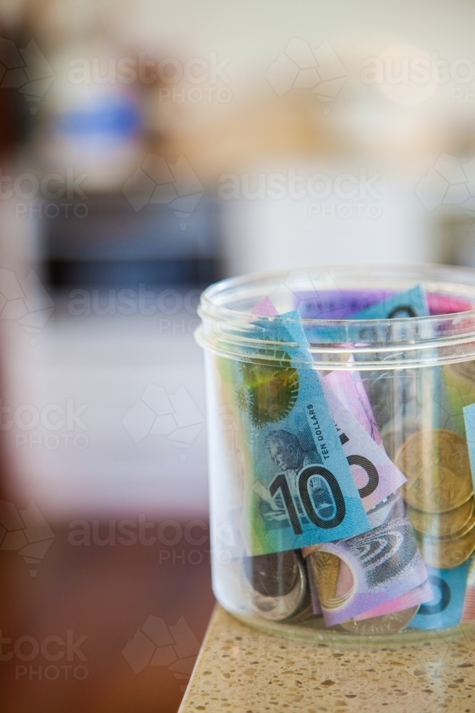 Australian money notes and coins in jar on counter - Australian Stock Image