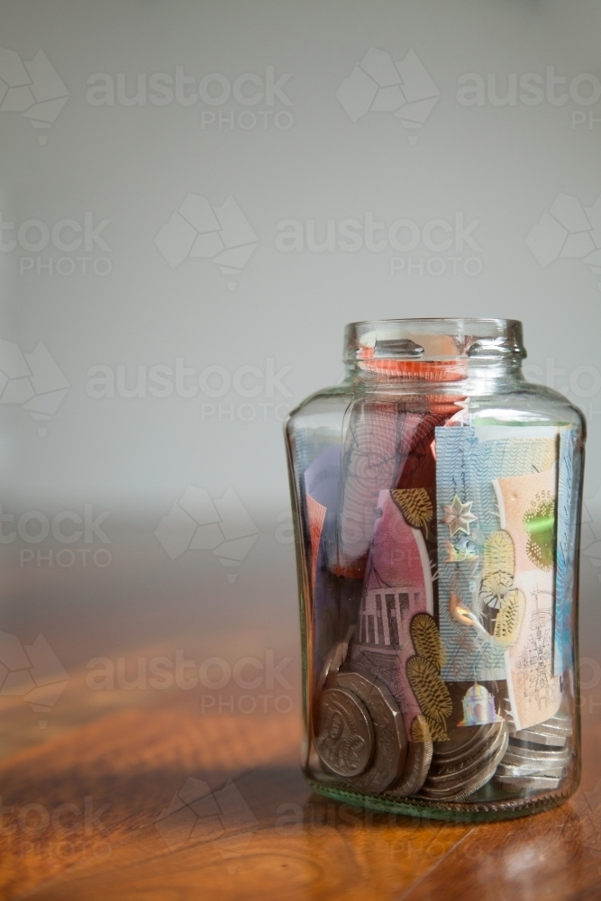 Australian money notes and coins in jar on wood with white copy space - Australian Stock Image