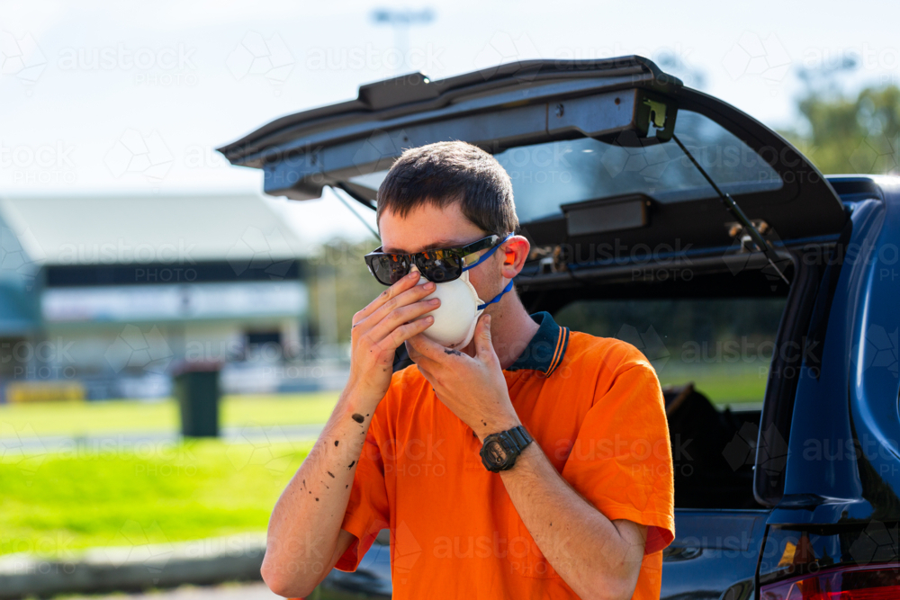 Australian teen trade apprentice putting on face dust mask personal protective safety equipment - Australian Stock Image