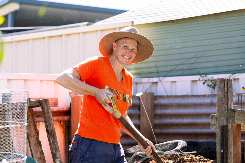 Australian woman in backyard garden ready to turn soil in compost container - Australian Stock Image