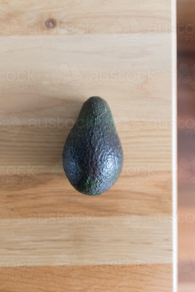 Avocado resting on a wooden table - Australian Stock Image