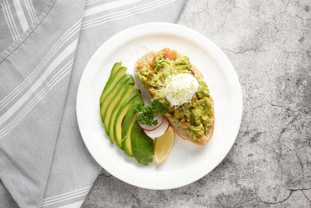 avocado toast served on plate with avocado slices on side of dish - Australian Stock Image