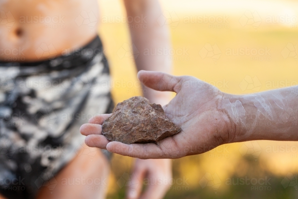 Axe head carved stone held in hand of aboriginal man - Australian Stock Image