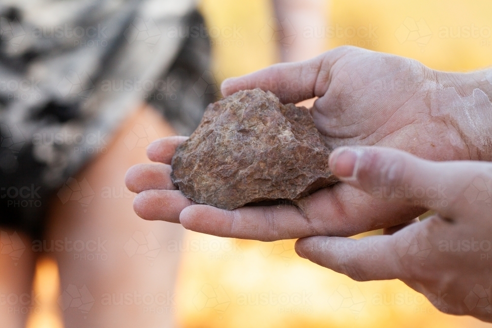 Axe head carved stone held in hand of aboriginal man - Australian Stock Image