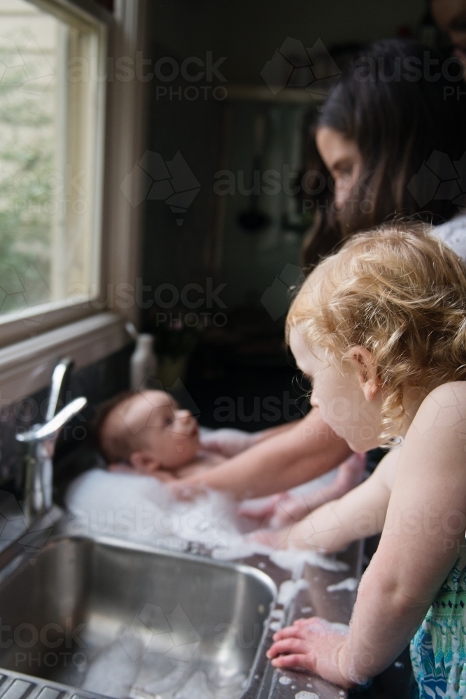 Baby bathtime in kitchen sink - Australian Stock Image