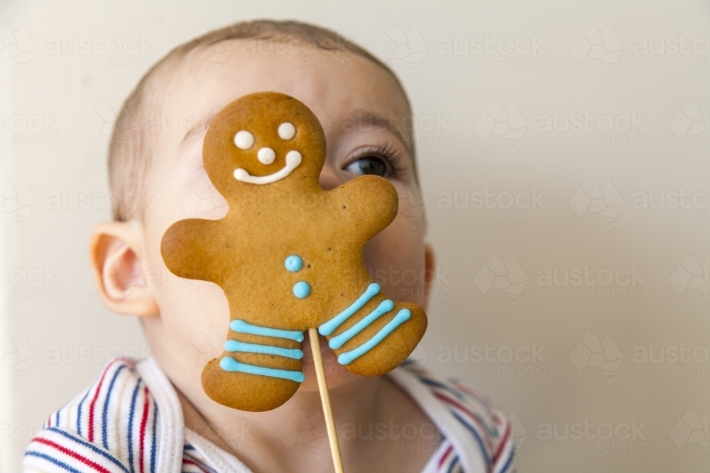 Baby boy holding gingerbread man biscuit - Australian Stock Image