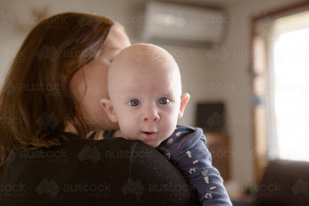 Baby boy looking over mothers shoulder - Australian Stock Image