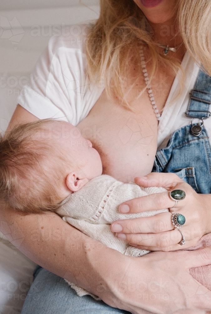 Baby breastfeeding in mothers arms. - Australian Stock Image