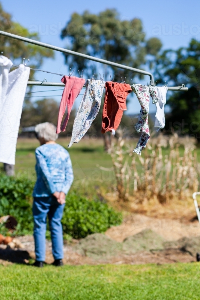 baby clothes hanging on farm washing line in sunlight - Australian Stock Image