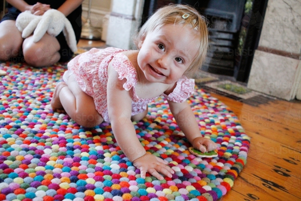 Baby girl crawling on a rug - Australian Stock Image