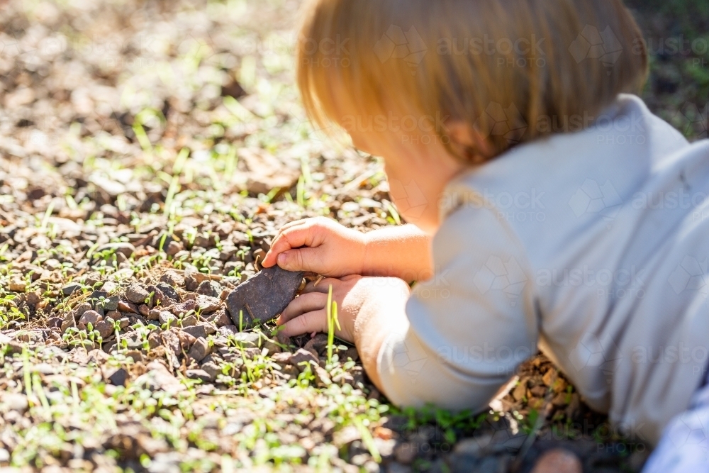 Playing Rocks Image of Baby girl lying on ground in gravel playing with rocks ...