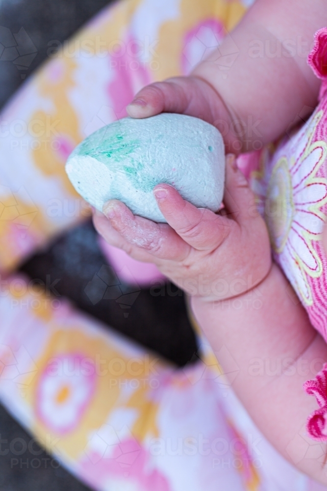 Baby hand holding chalk to draw with - Australian Stock Image