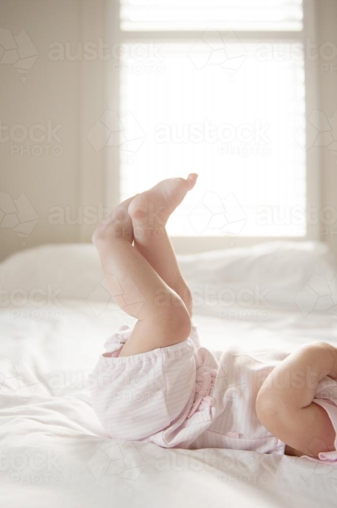 Baby laying on her back with feet in the air - Australian Stock Image