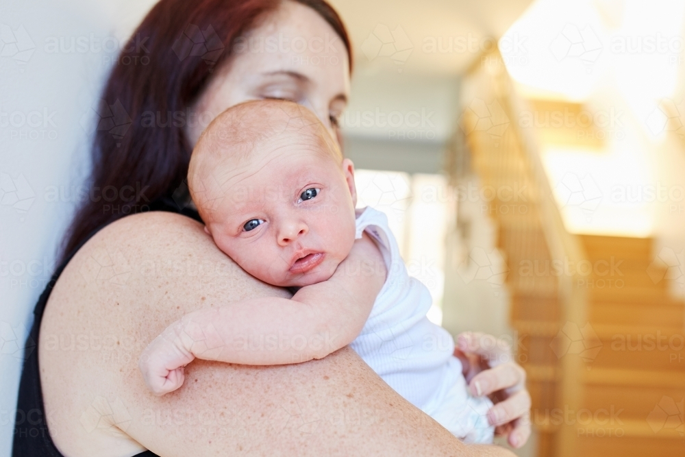 Baby leaning against shoulder while being held by her mother - Australian Stock Image