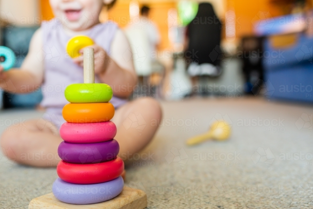 Baby learning through play developing fine motor skills with colourful stacking toy - Australian Stock Image