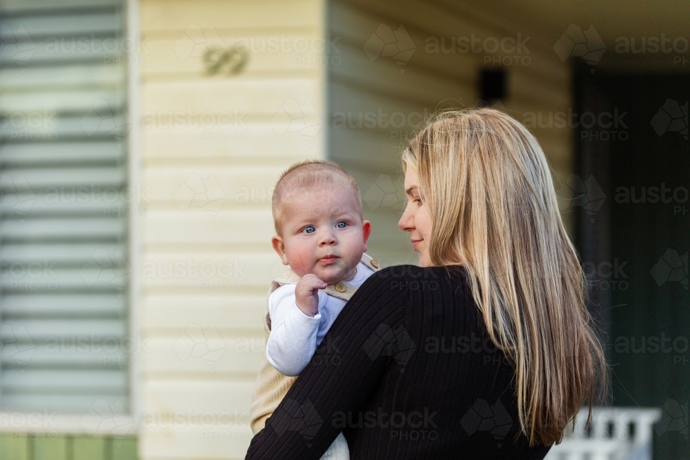 Baby looking over his mother's shoulder outside home - Australian Stock Image