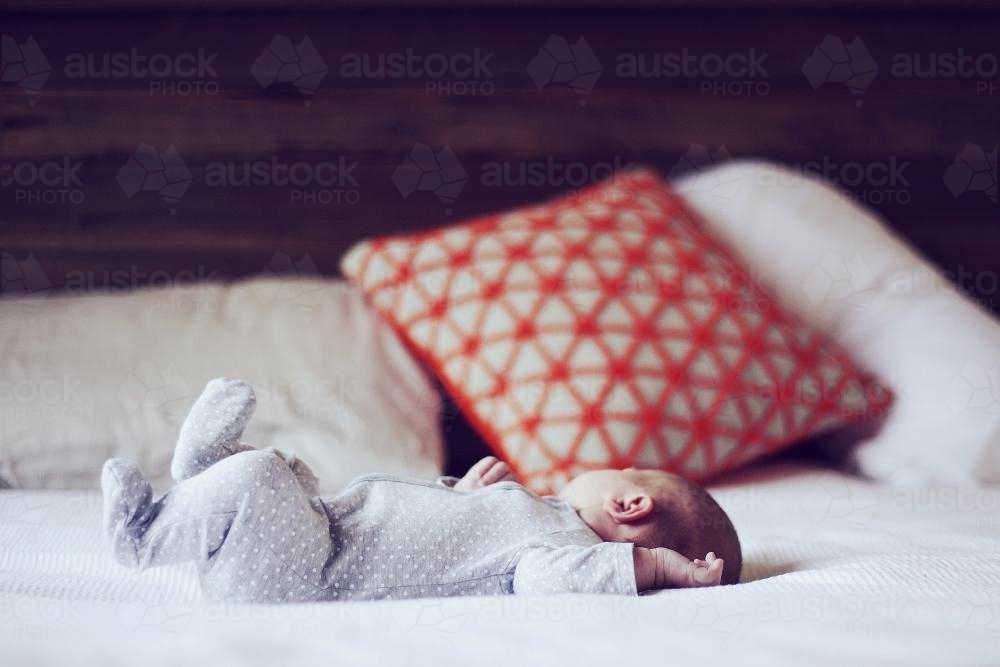 Baby on its back on a bed - Australian Stock Image