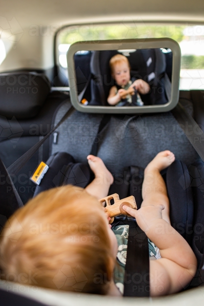 Image of Baby playing in car with wooden toy car while travelling Austockphoto