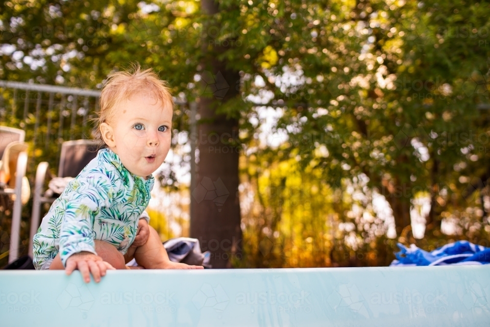 Baby with ooh face excited at the edge of a inground pool - Australian Stock Image