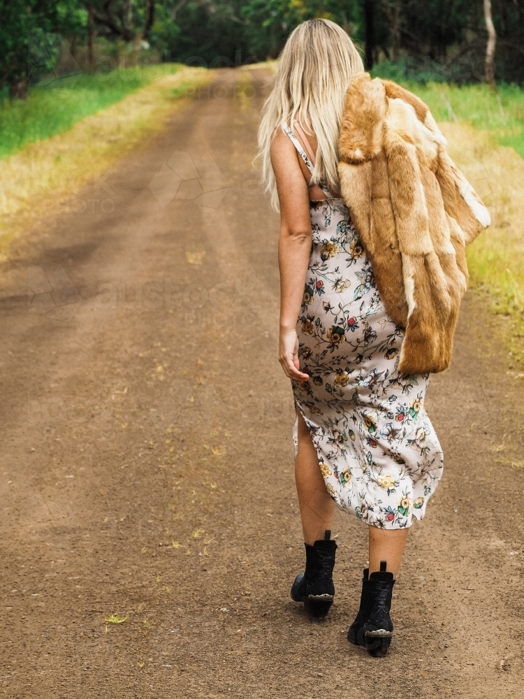 Back view of girl walking down a country dirt track. - Australian Stock Image