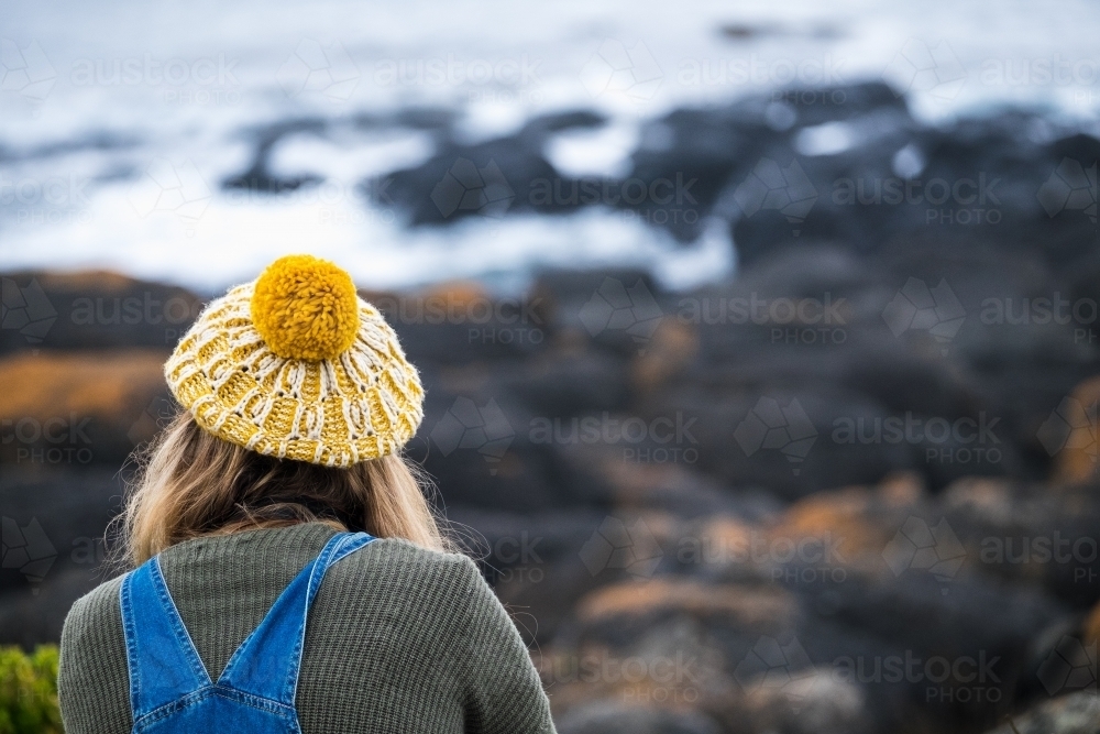 Back view of girl wearing hand knitted beanie and overalls - Australian Stock Image