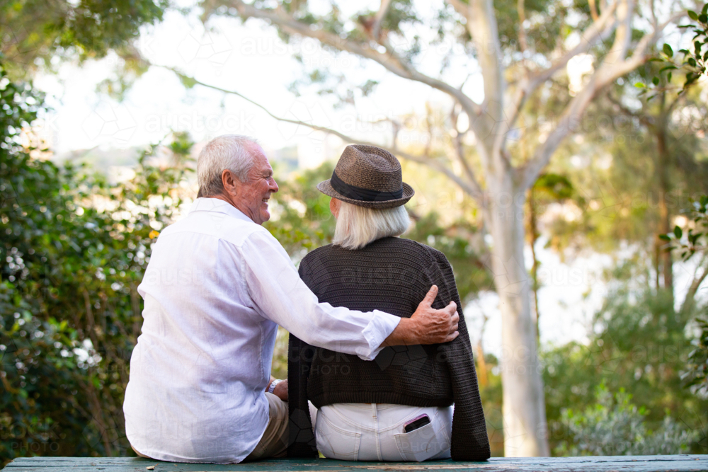 Image of Back view of Senior couple sitting on park bench - Austockphoto