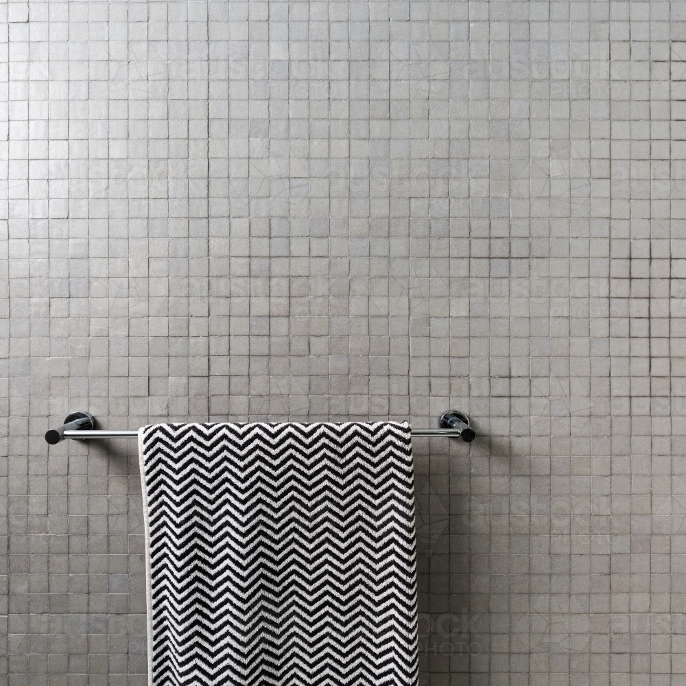 Image of Background of mosaic square wall tiles with chevron towel on chrome towel rail Austockphoto