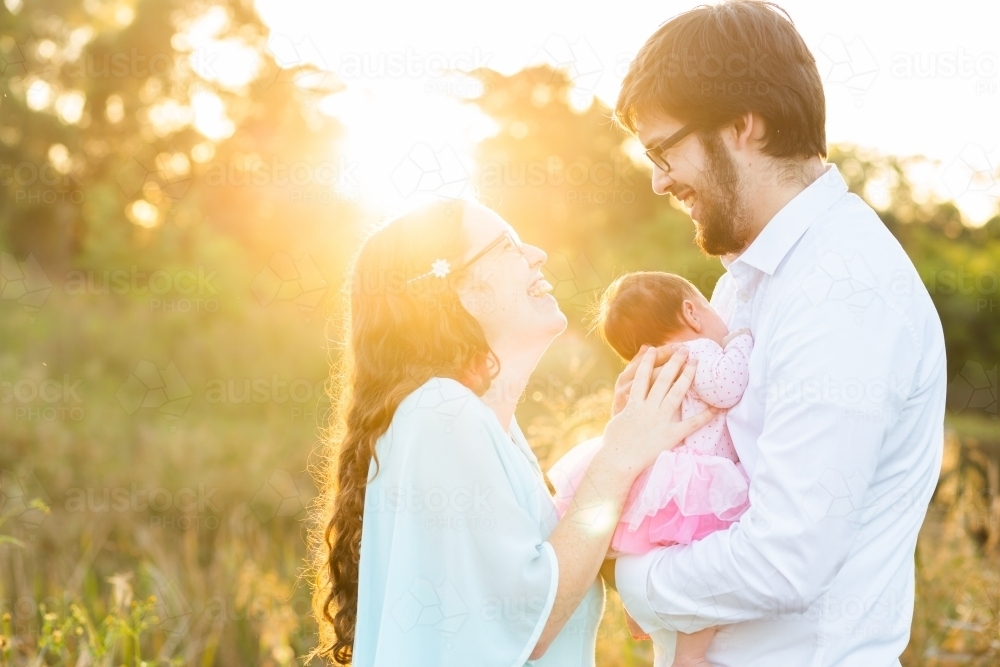 Backlit joyful family with newborn baby girl outside in Aussie sunlight - Australian Stock Image