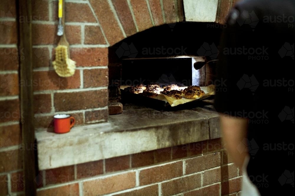 Baker putting pastries into oven - Australian Stock Image