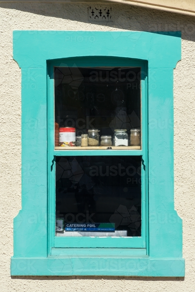 Baking ingredients sitting on shelves in a brightly painted kitchen window - Australian Stock Image