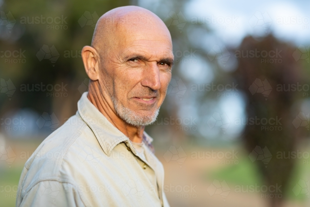 bald man outdoors with blurred bush background - Australian Stock Image