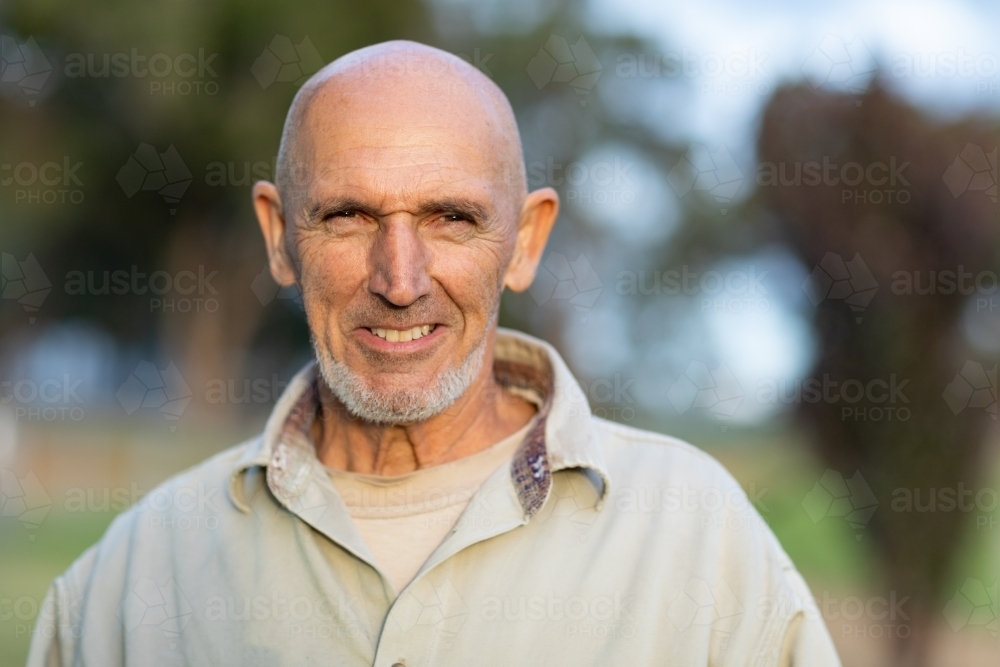 bald mature man head and shoulders smiling and looking at camera - Australian Stock Image