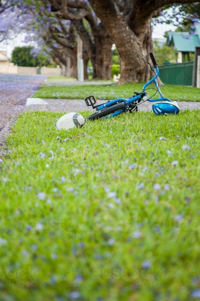 Ball, bicycle and helmet left behind by kid on the roadside - Australian Stock Image