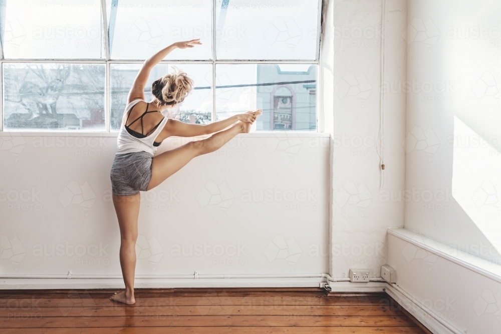 Ballet dancer practicing poses in a bright white studio - Australian Stock Image