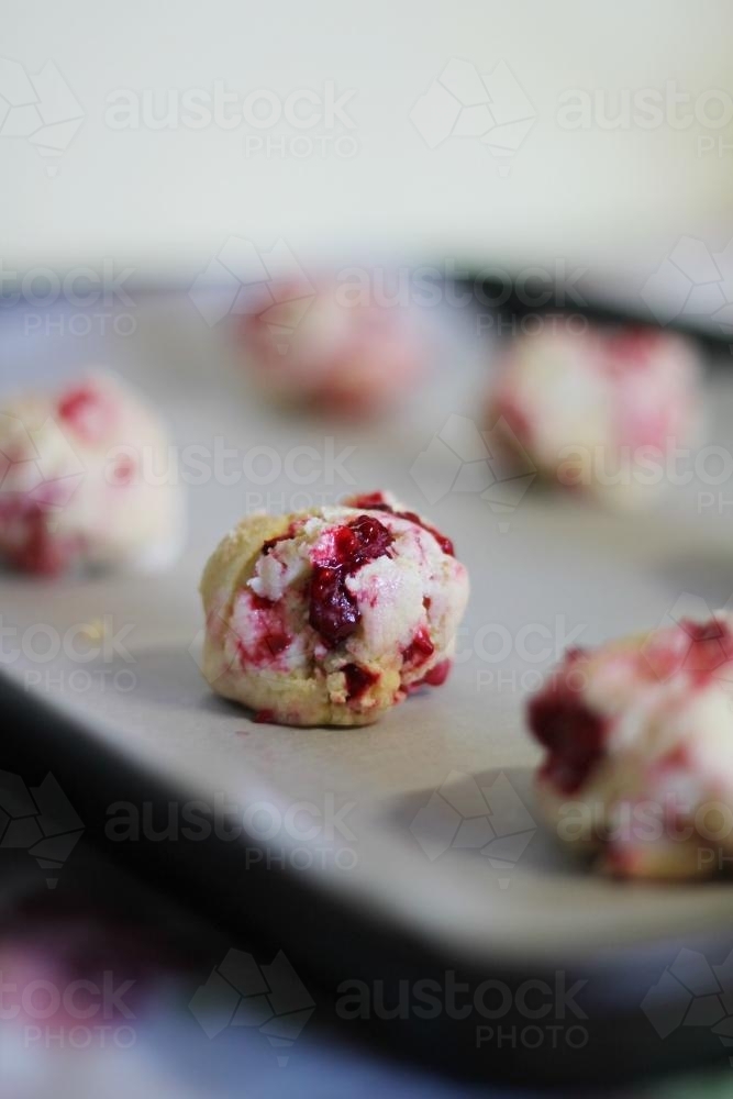 Balls of raspberry biscuit dough sitting on a tray - Australian Stock Image