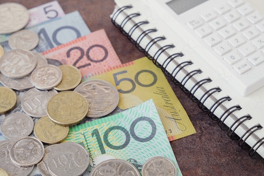 Banknote and coins with notebook and calculator - Australian Stock Image