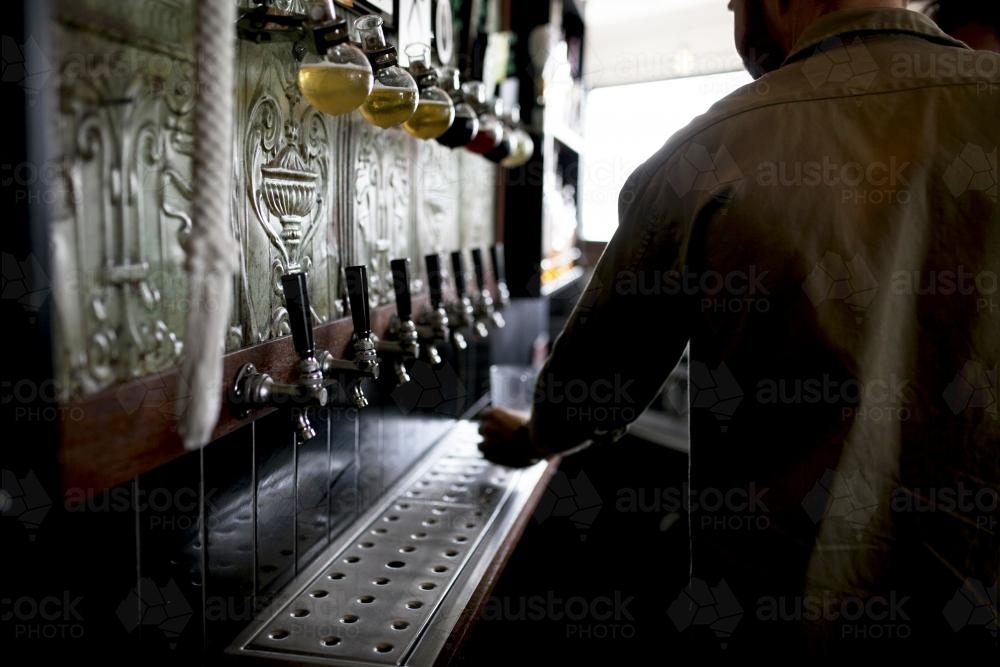 Bartender pouring drink on tap at local craft beer bar - Australian Stock Image