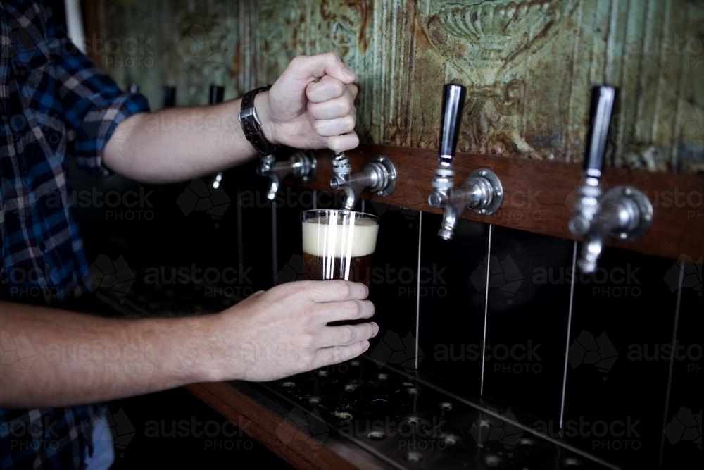 Image of Bartender pouring drink on tap at local craft beer bar