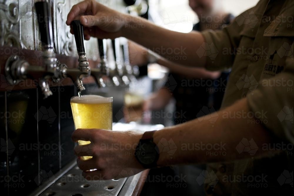 Bartenders pouring drinks from tap at local craft beer bar - Australian Stock Image