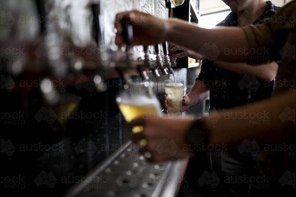 Bartenders pouring drinks on tap at local craft beer bar - Australian Stock Image