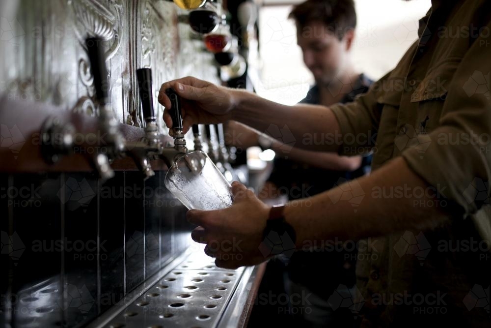 Bartenders pouring drinks on tap at local craft beer bar - Australian Stock Image