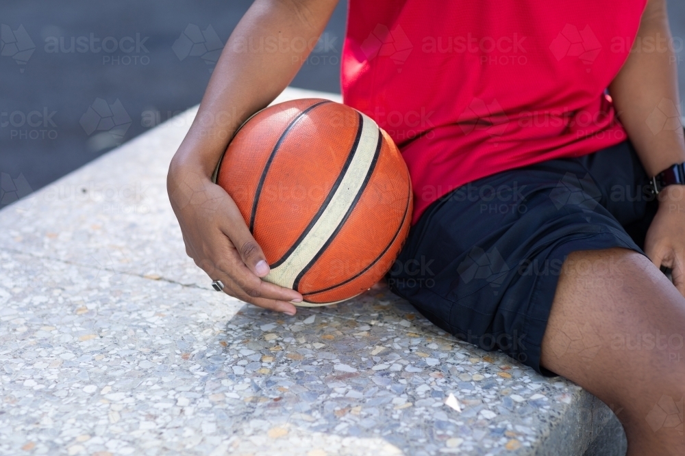 Image of basketball being held by player on sidelines Austockphoto