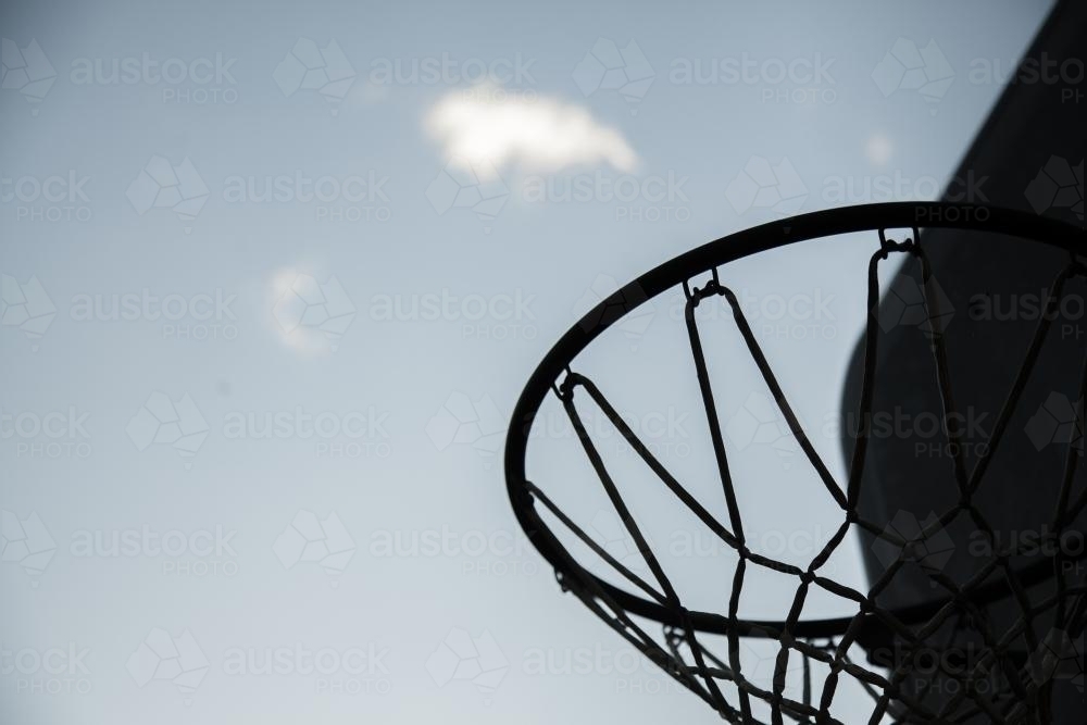Basketball hoop and net silhouetted against the sky - Australian Stock Image