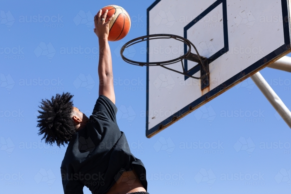 Basketball hoop with young guy about to slam a goal - Australian Stock Image