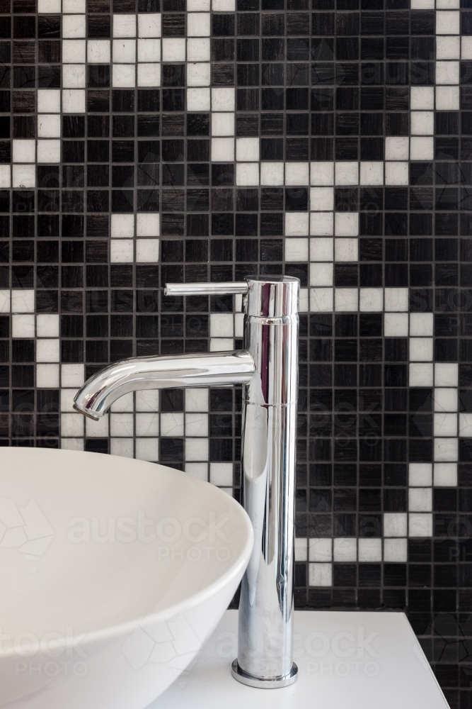 bathroom sink with chrome tap and black and white mosaic tiles - Australian Stock Image