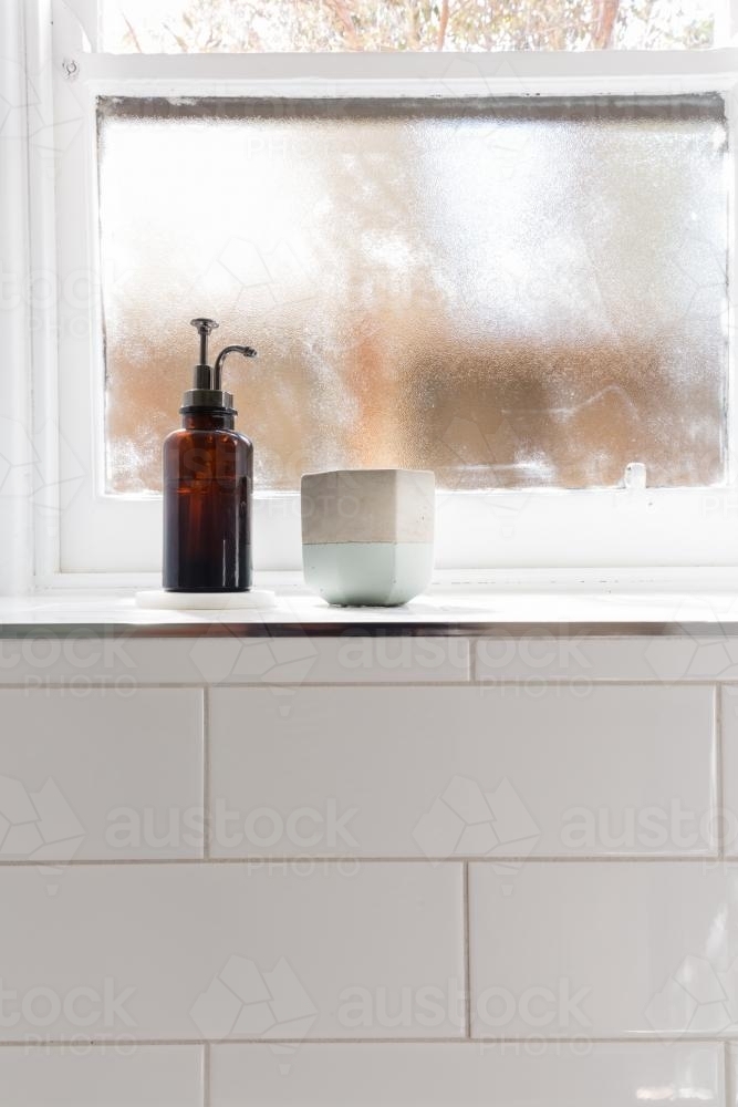 Bathroom soap dispenser and pot on window ledge with background of negative space for text - Australian Stock Image